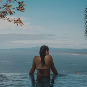 Frau-genießt-den-blick-aus-dem-infinity-pool-auf-das-meer-und-eine-atmosphäre-von-ruhe-und-exklusivität
