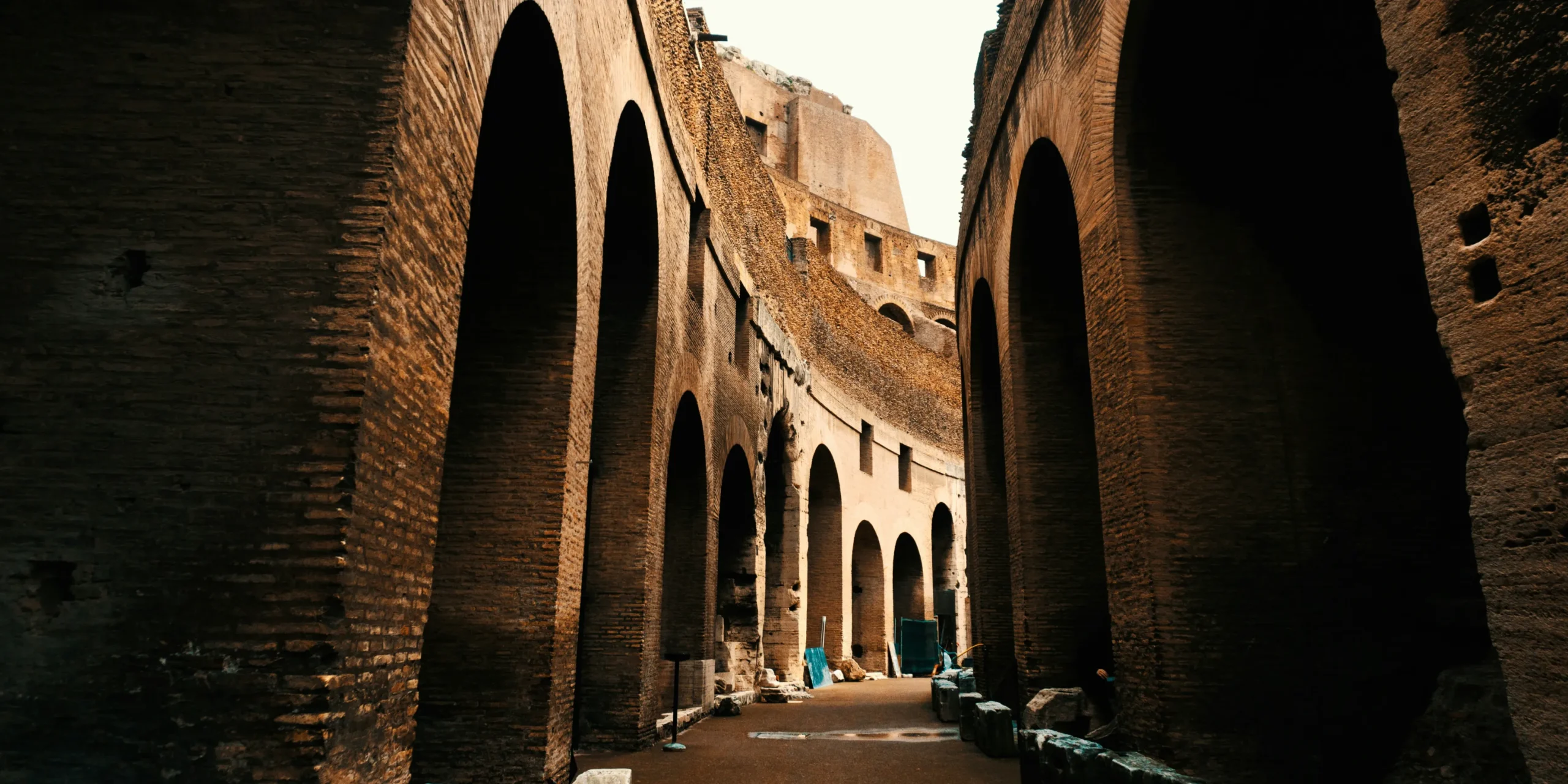 Geschichte-duftmarketing-roemisches-amphi-theater | zaluti b. V. Blick in einen überdachten gang mit bögen und ziegelmauern in einem römischen amphitheater – diese antike architektur erinnert an öffentliche veranstaltungen, bei denen düfte zur stimmung beitrugen und ein vorläufer des duftmarketings waren.