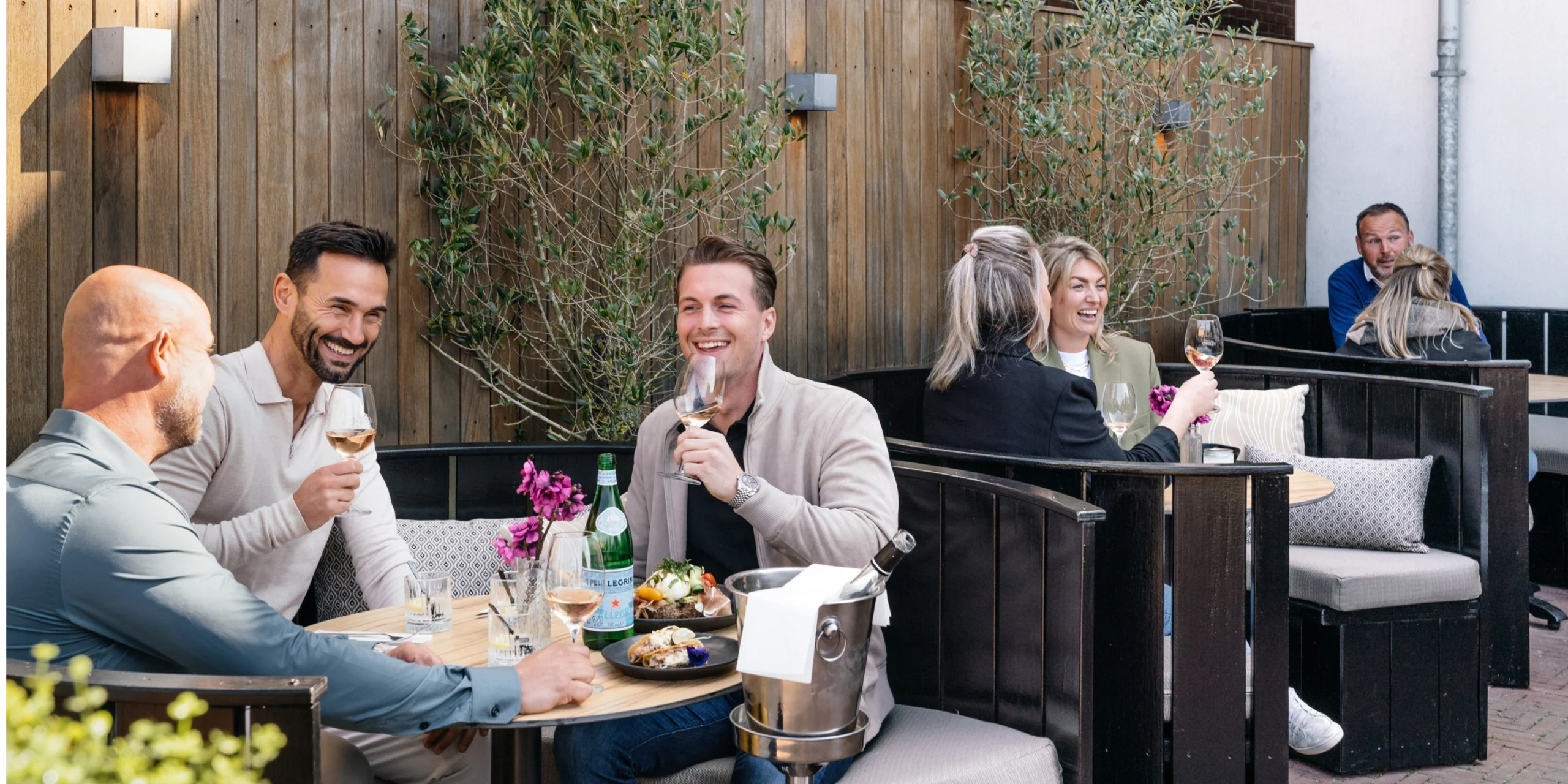 dining outdoors at a cozy, modern terrace with wine and shared dishes.
