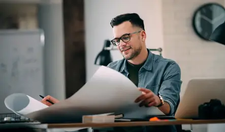 An architect is reviewing blueprints in a modern office.