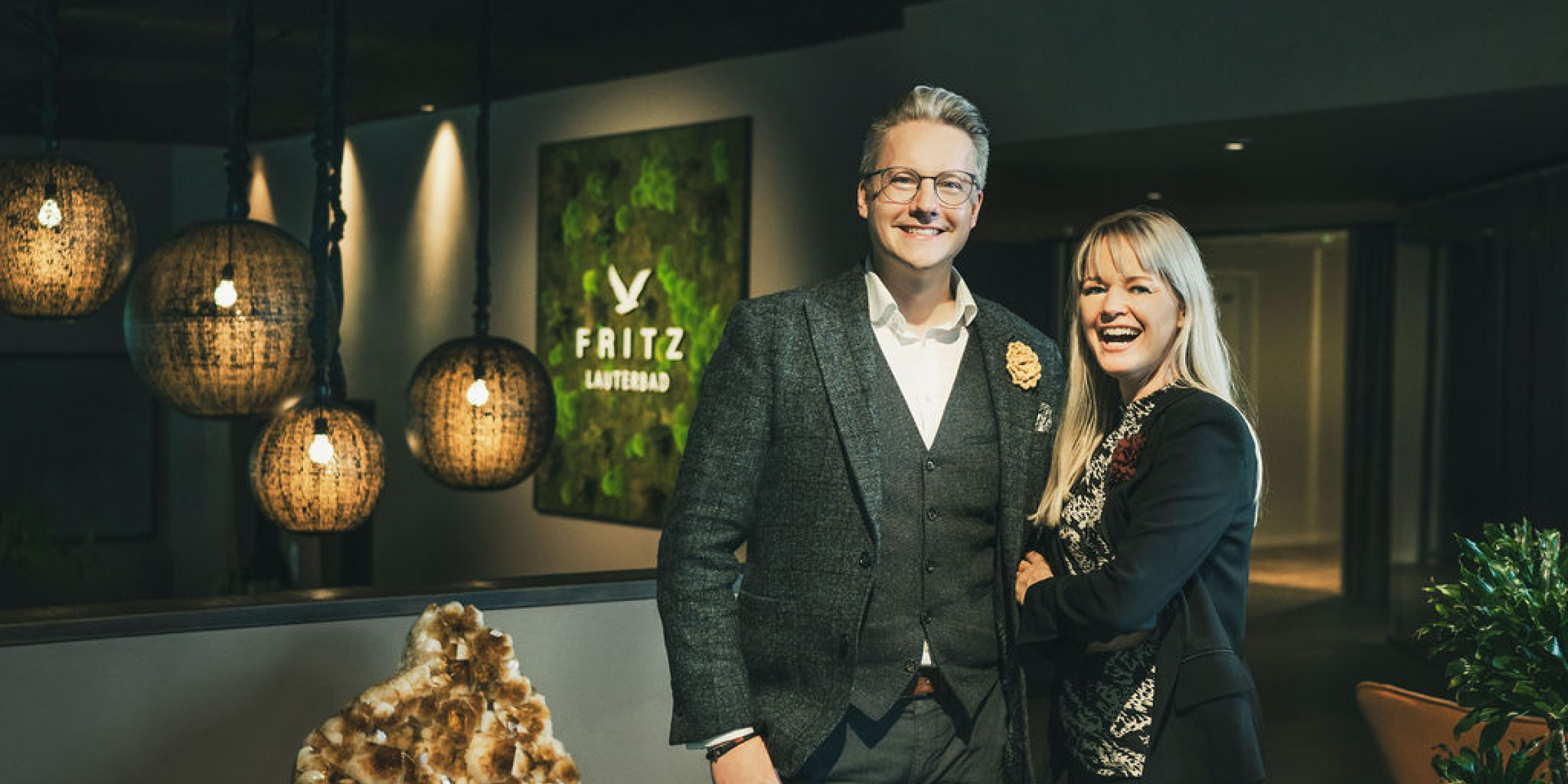 Smiling hotel owners standing in the lobby of hotel fritz lauterbad, symbolizing hospitality and the welcoming atmosphere enhanced by scent marketing.