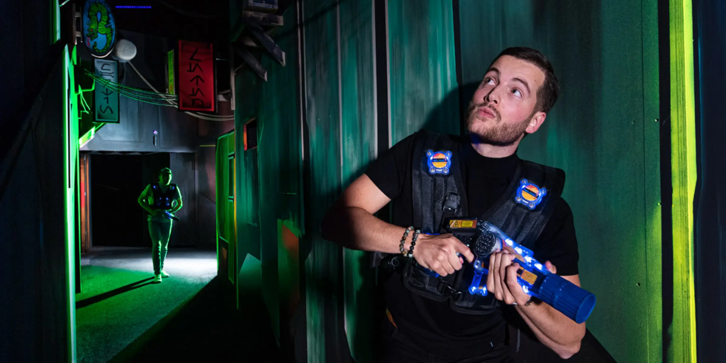 Man playing laser tag in a neon-lit arena at planet awesome, illustrating the immersive experience enhanced by scent marketing.