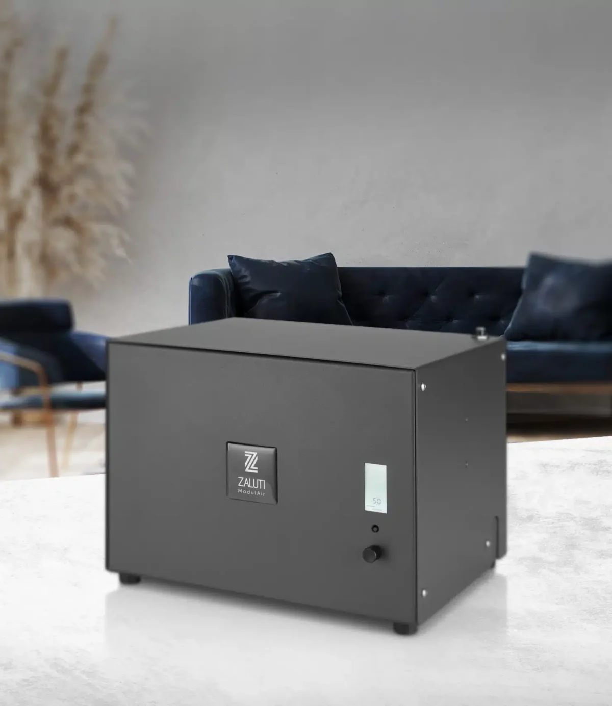 Zaluti ModulAir scent machine placed in a modern living room interior with a blue sofa in the background.
