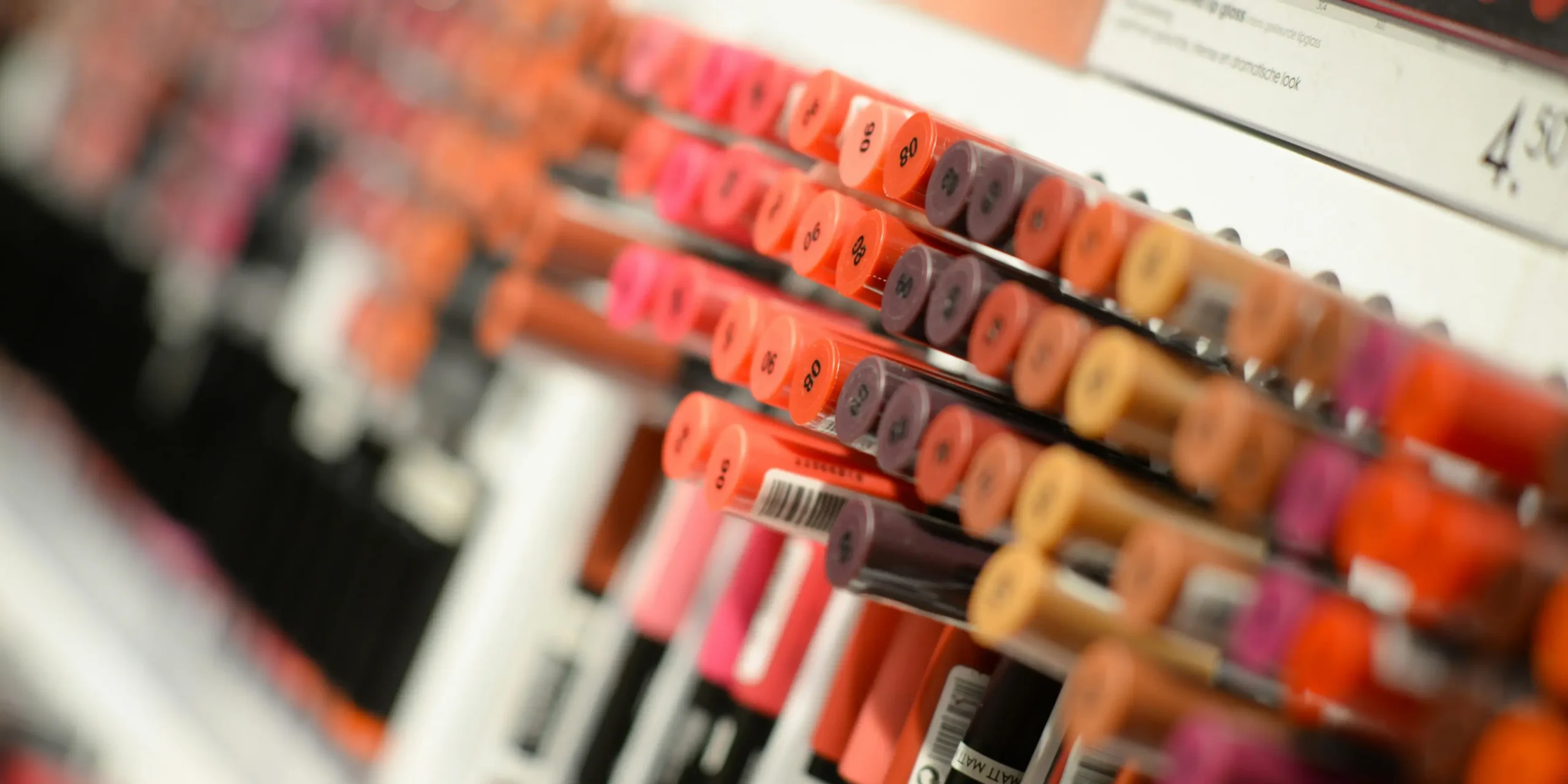 Best-scent-machines-stores-lipstick-display | zaluti b. V. Close‑up of a rack of colourful lipsticks in a cosmetics store, with a scent machine subtly enhancing the shopping experience.