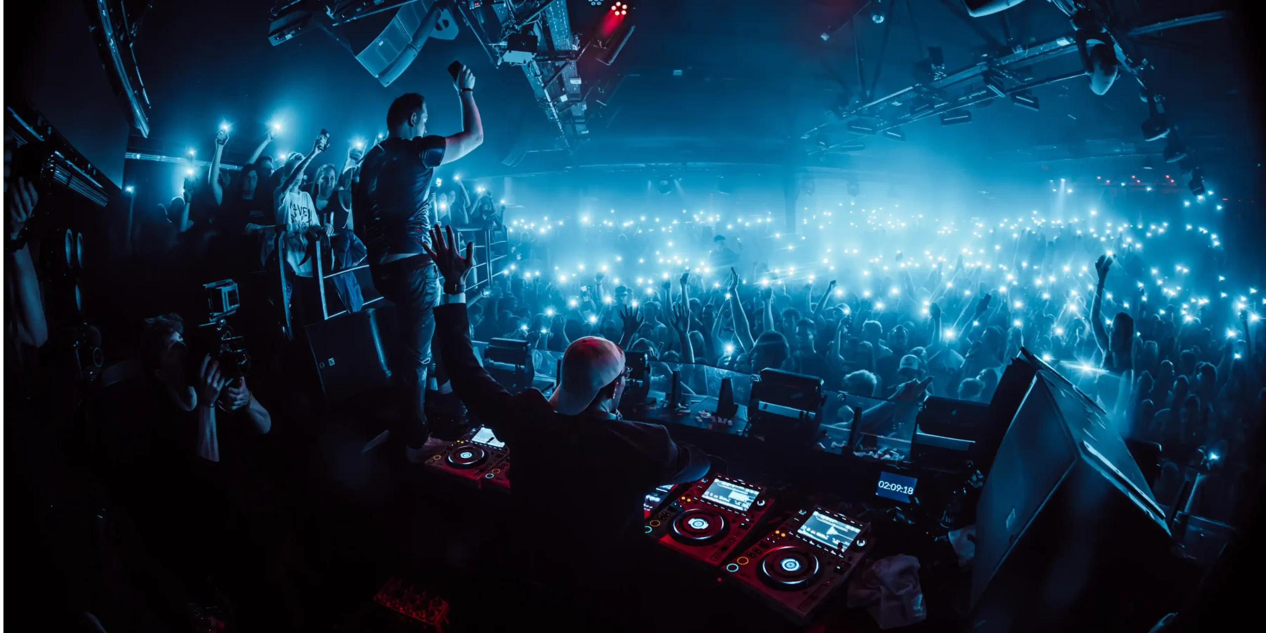 Odour-neutralization-nightclub-dj-and-crowd-with-phones | zaluti b. V. A dj performs in a crowded nightclub while a large crowd holds up their phones with lights; in such environments, odor neutralization is essential.